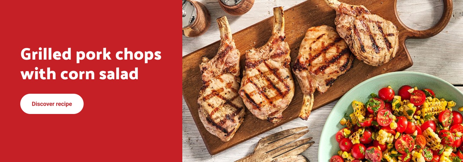 Grilled pork chops with corn salad. Discover recipe.' Image shows four grilled pork chops on a wooden board beside a bowl of corn and tomato salad.
